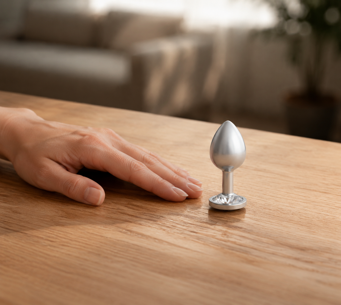 Schaalbeeld van de middelgrote zilveren buttplug met witte diamant naast een hand
