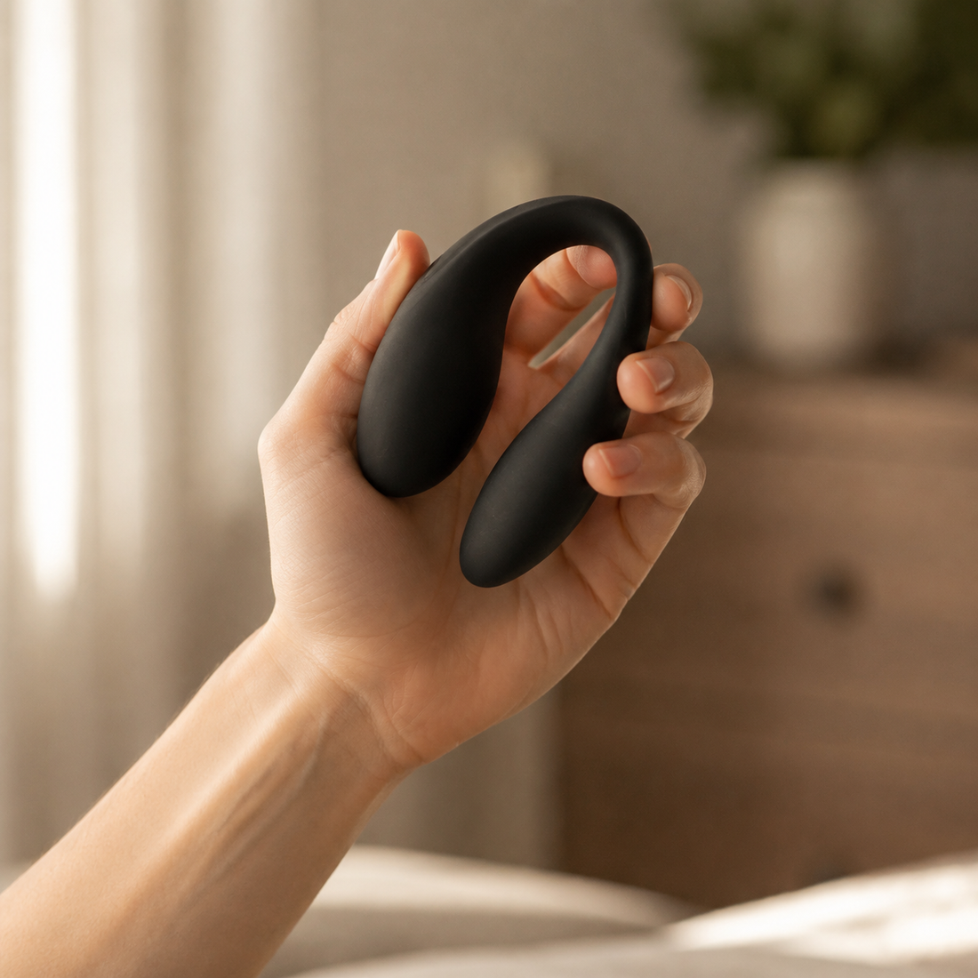 Hand houdt matzwarte U-vormige FlexToyz koppelvibrator voor schaalweergave