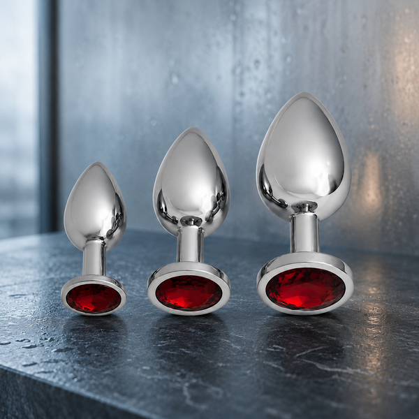 Drie zilveren FlexToyz buttplugs met rode diamant op een koele donkerblauwe stenen ondergrond