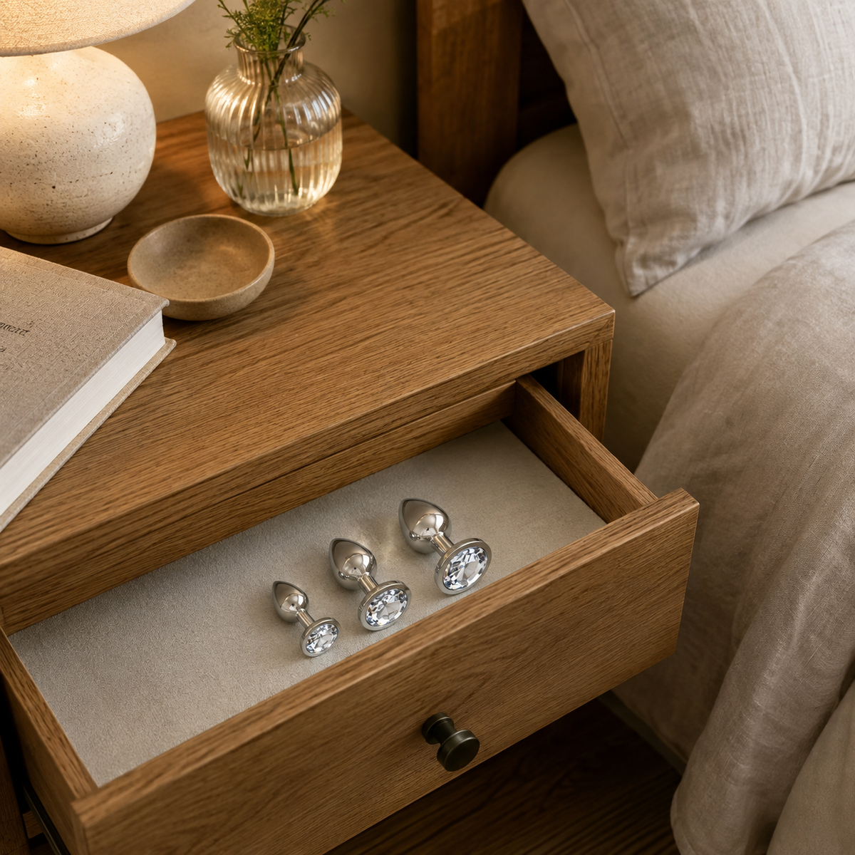 Zilveren buttplug set met witte diamant in een open lade van een houten nachtkastje