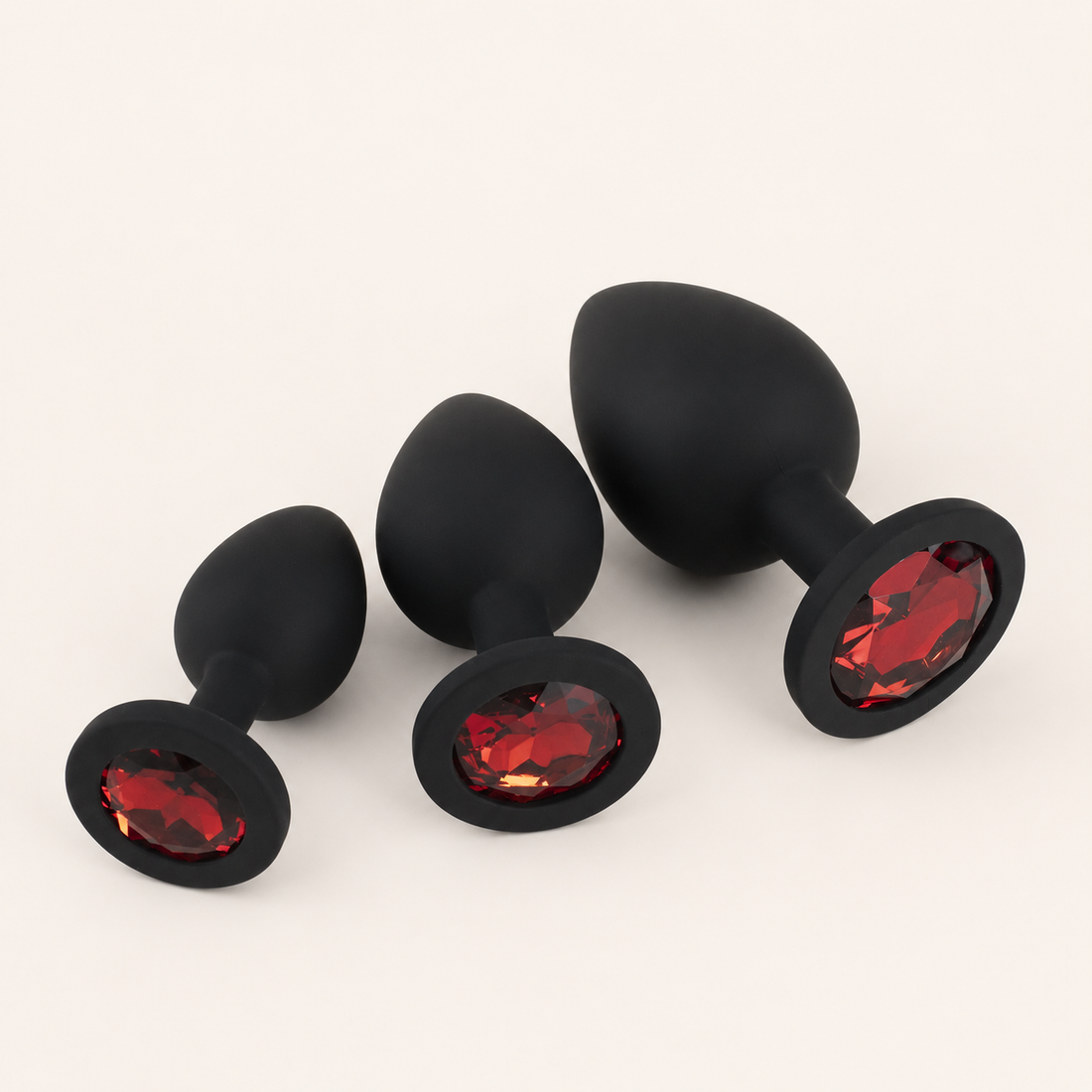 Zwarte siliconen FlexToyz buttplug set met drie maten en rode diamant op neutrale achtergrond