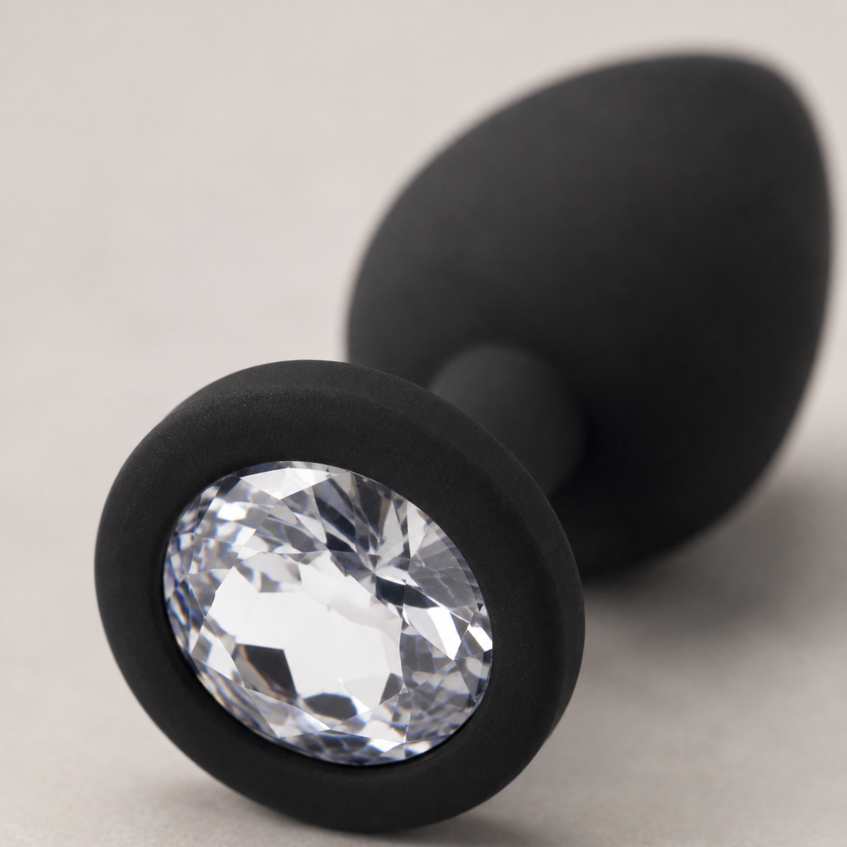 Macrodetail van heldere witte diamant in zwarte siliconen basis van FlexToyz buttplug
