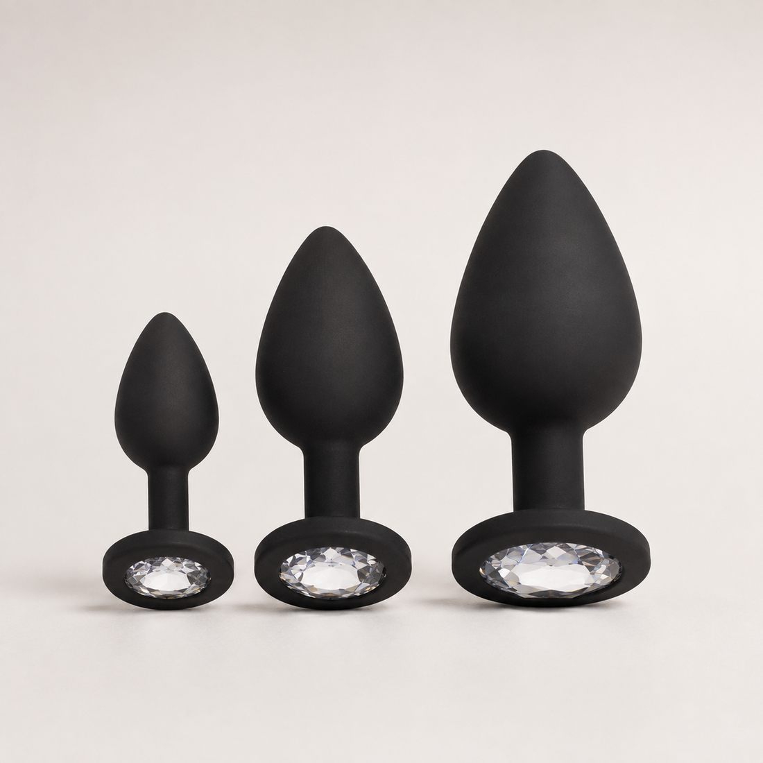 FlexToyz zwarte siliconen buttplug set met witte diamant in drie maten op neutrale achtergrond