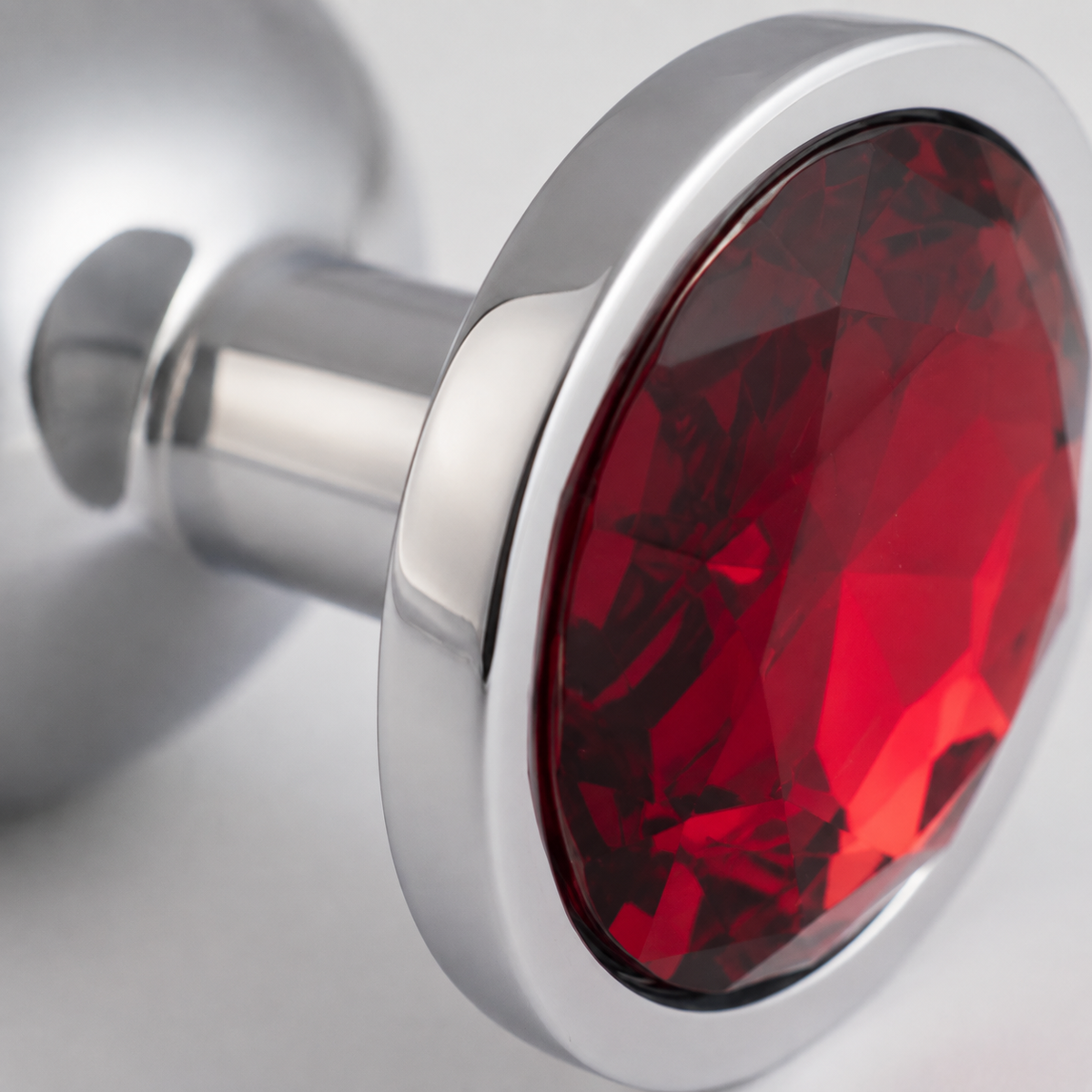 Macrodetail van de rode kristalfacetten en gepolijste zilveren rand van de grote buttplug
