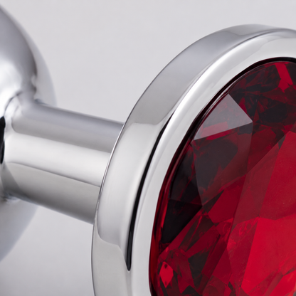 Macrodetail van de rode kristalfacetten en gepolijste zilveren rand van de middelgrote buttplug