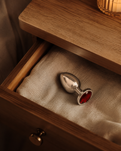 Middelgrote zilveren buttplug met rode diamant stijlvol opgeborgen in een nachtkastlade