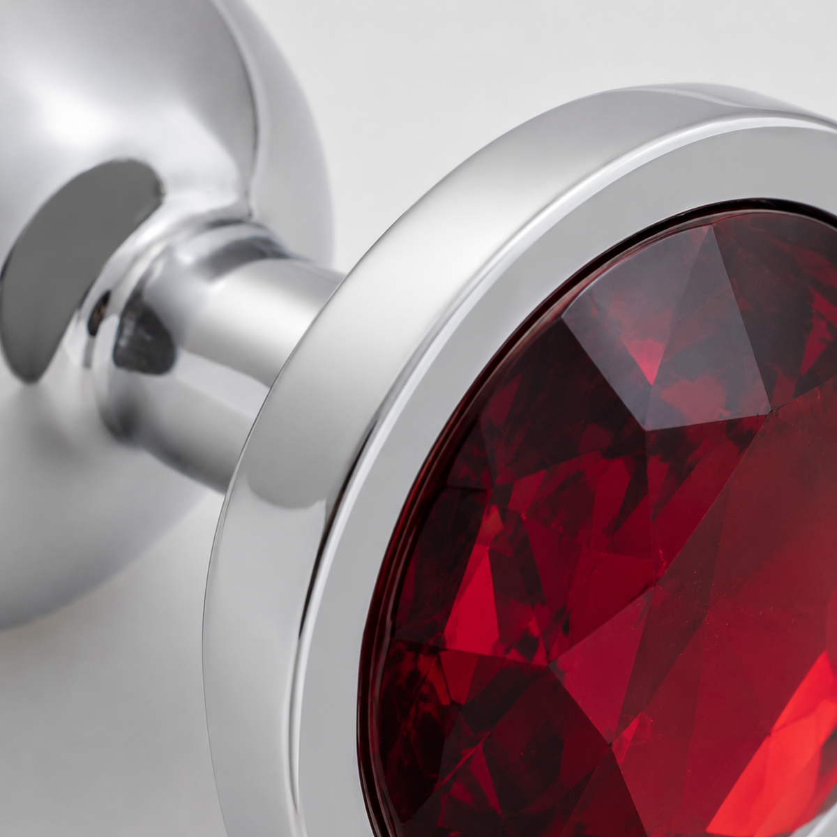 Macrodetail van de rode kristalfacetten en zilveren rand van de kleine buttplug