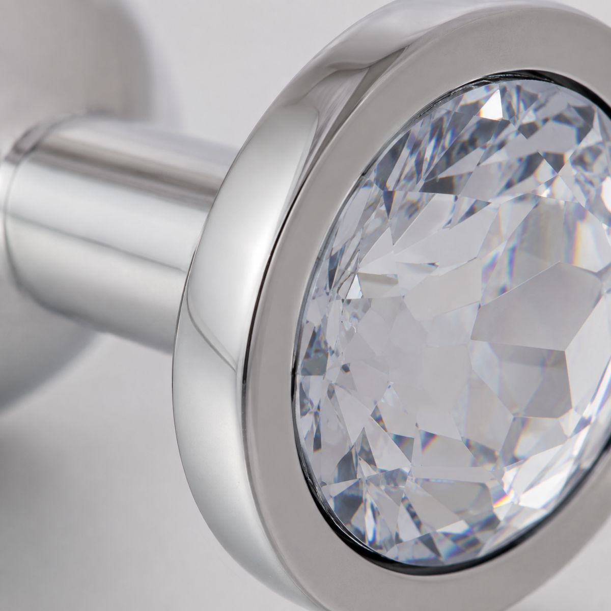 Macrodetail van de witte kristalfacetten en gepolijste zilveren rand van de grote buttplug
