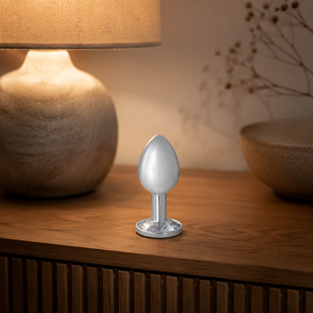 Grote zilveren buttplug met witte diamant stijlvol geplaatst op een warm nachtkastje