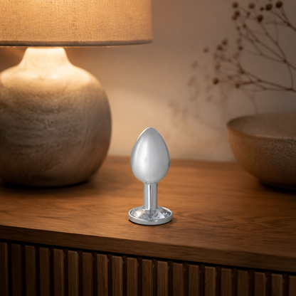 Grote zilveren buttplug met witte diamant stijlvol geplaatst op een warm nachtkastje