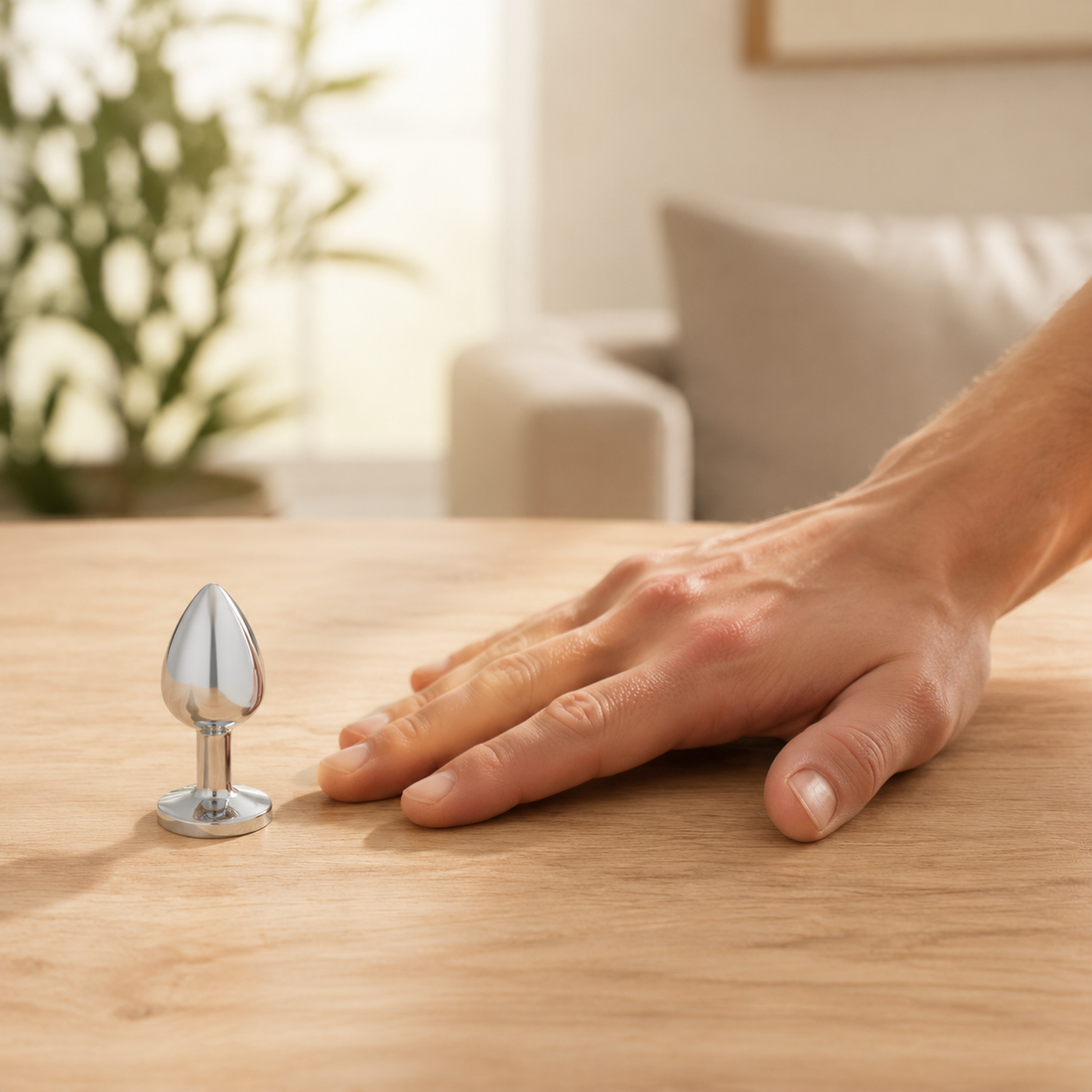 Schaalbeeld van de grote zilveren buttplug met witte diamant naast een hand
