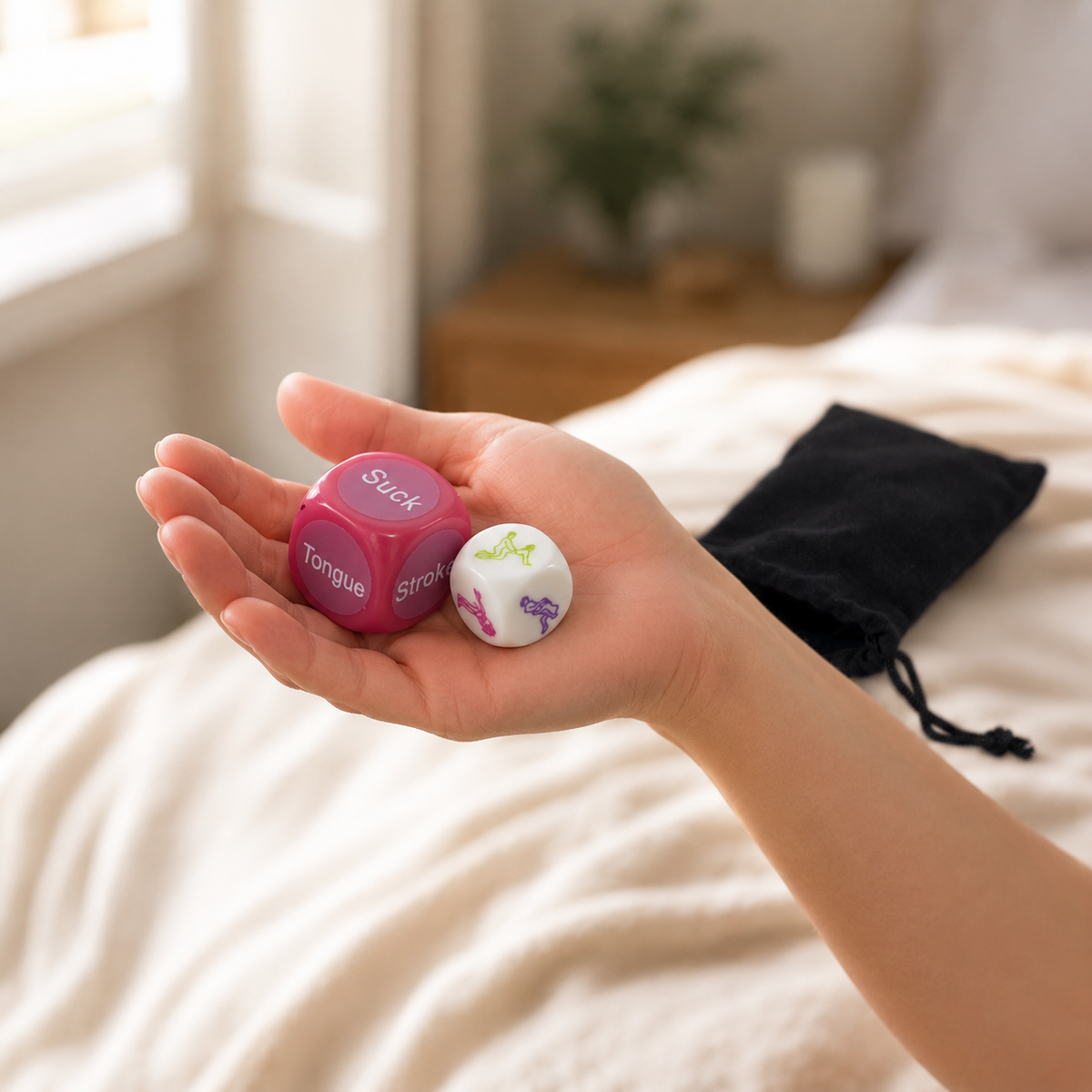 Hand houdt roze en witte FlexToyz Kama Sutra dobbelstenen met zwart opbergzakje op de achtergrond