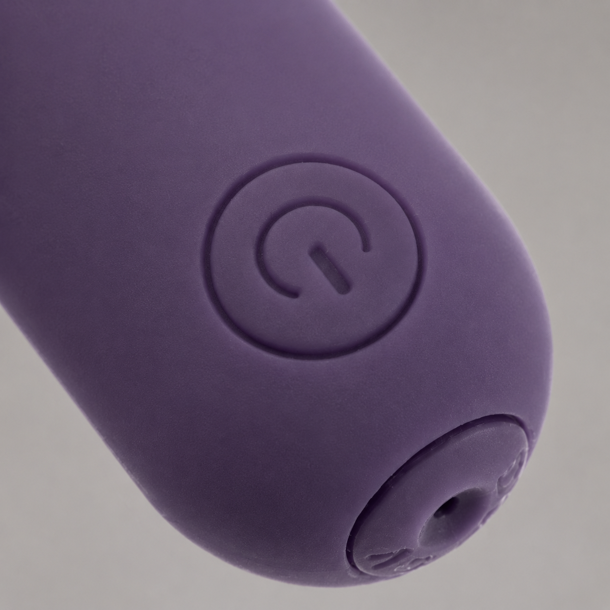 Macrodetail van ronde powerknop en laadaansluiting van paarse FlexToyz bullet vibrator
