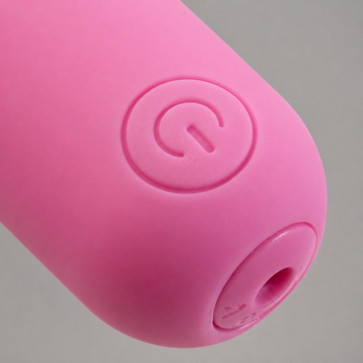 Macrodetail van ronde powerknop en laadaansluiting van roze FlexToyz bullet vibrator