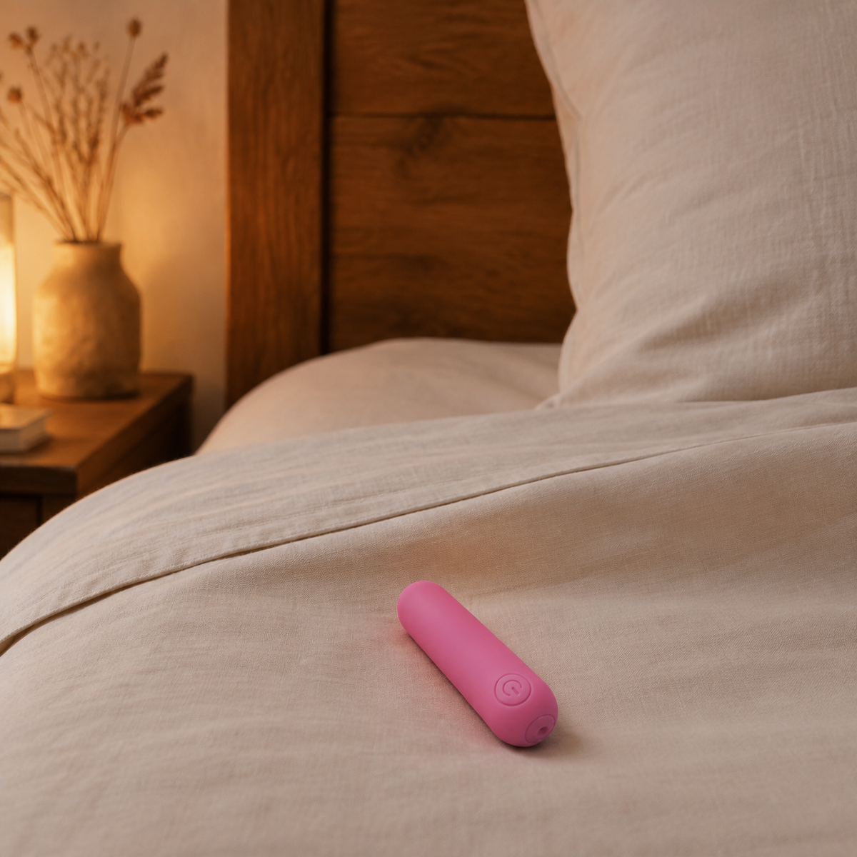 Roze FlexToyz bullet vibrator op warm ivoorkleurig bedlinnen in een slaapkamer