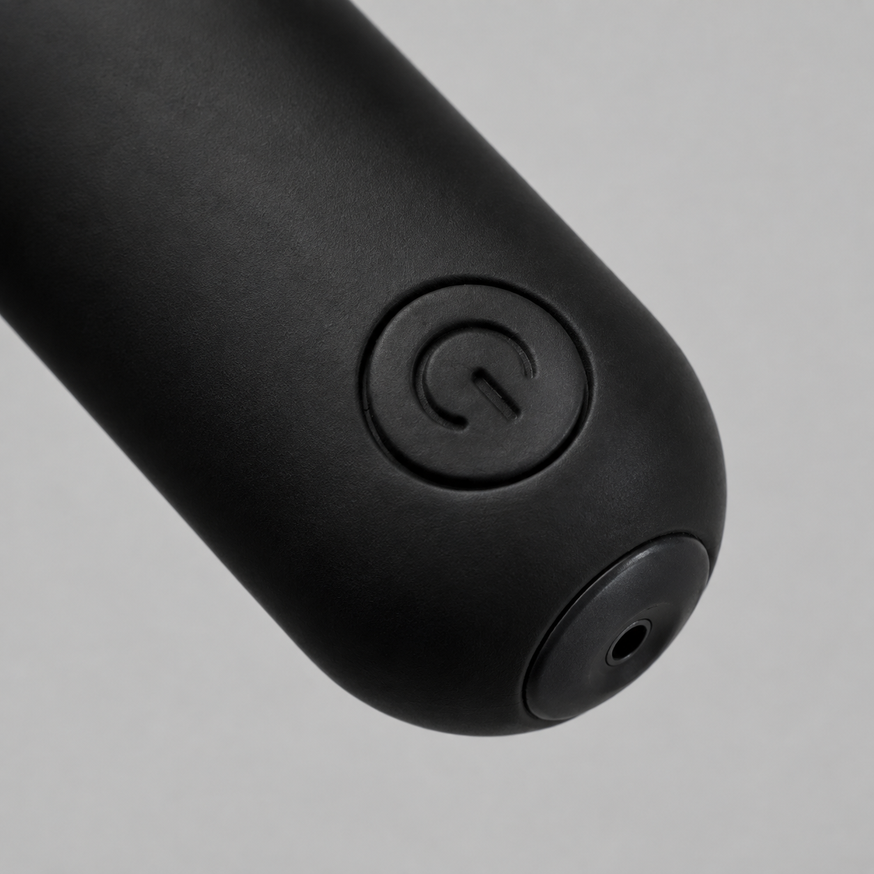 Macrodetail van ronde powerknop en laadaansluiting van zwarte FlexToyz bullet vibrator