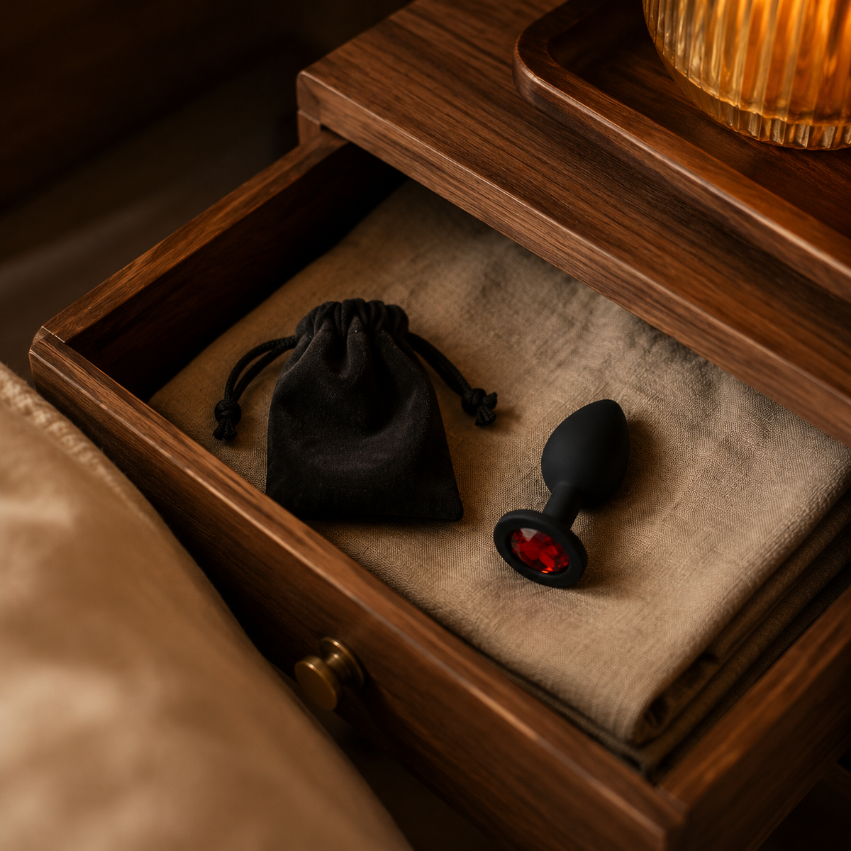 Zwarte FlexToyz buttplug Large met rode diamant in een warme nachtkastlade