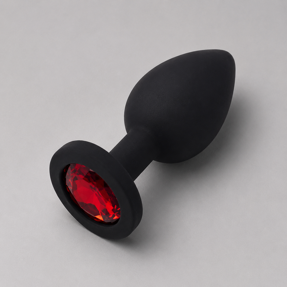 Zwarte siliconen FlexToyz buttplug Medium met rode diamant op lichtgrijze achtergrond