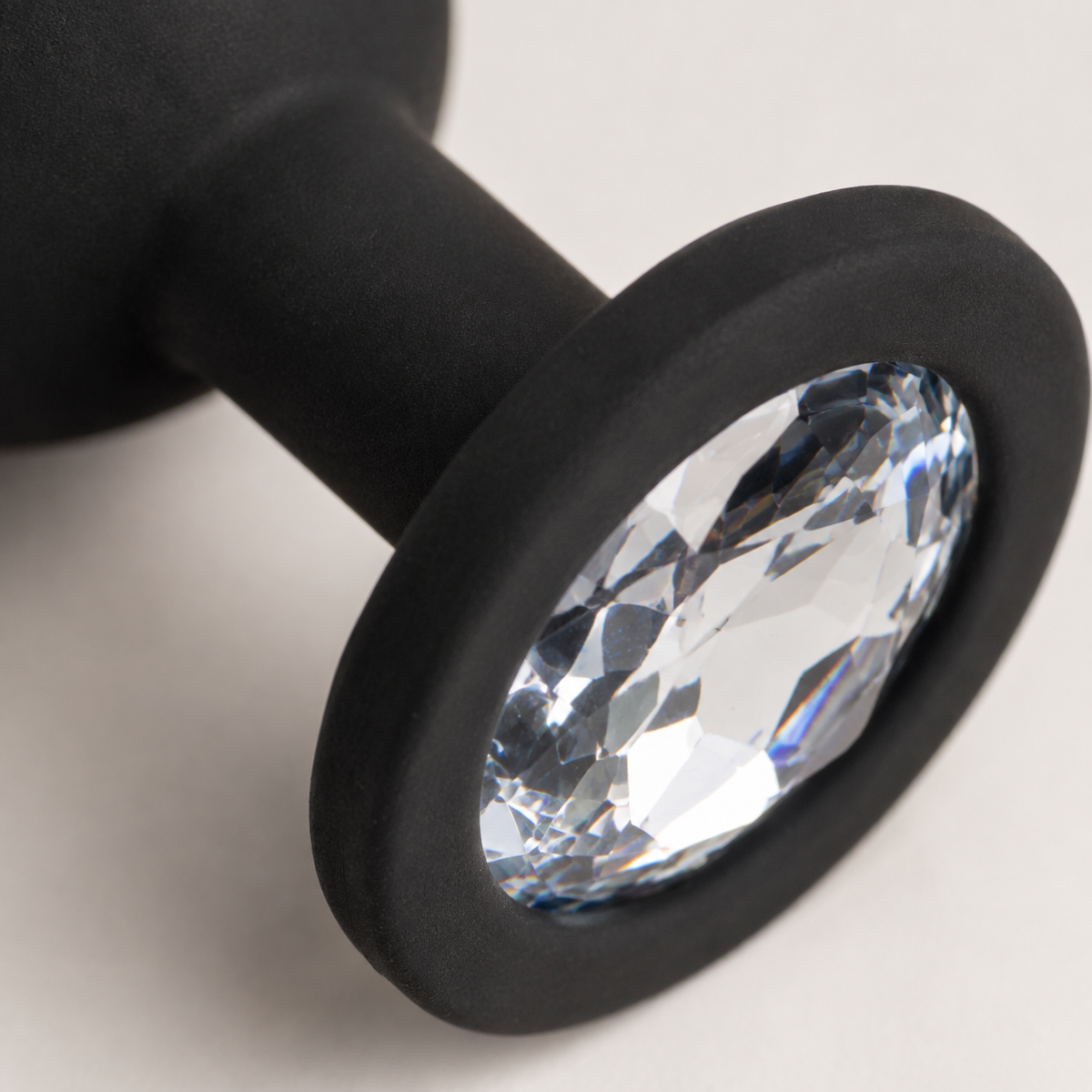 Macrodetail van witte diamant en matzwarte siliconen basis van FlexToyz buttplug Small