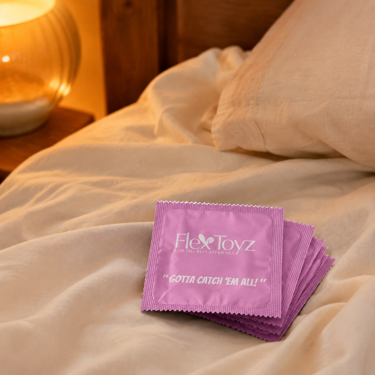 Stapel roze FlexToyz condoomverpakkingen op warm ivoorkleurig bedlinnen